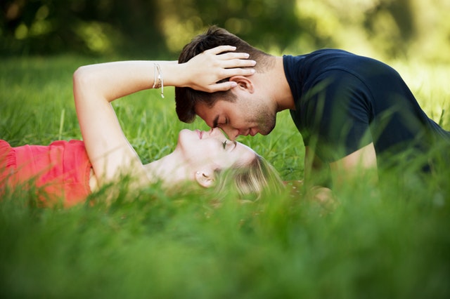 couple laying on grass facing each other