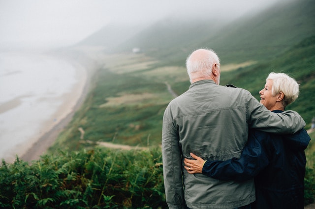 elderly couple standing outdoors looking lovingly into each others eyes