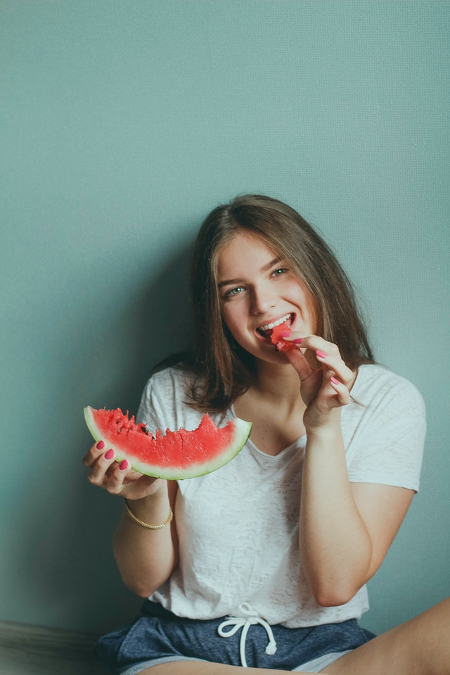 woman eating a watermelon slice indoors