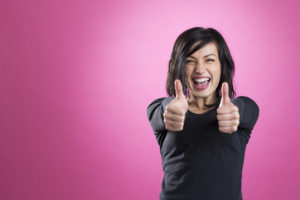 stock image of woman smiling with both thumbs pointing up