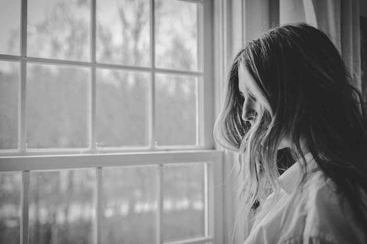 depressed woman looking out of window