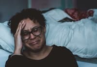 woman crying on the floor next to a bed