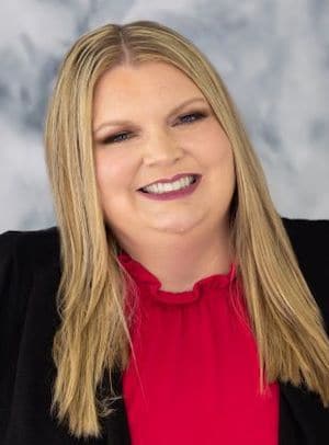 Therapist Susan Goodenberger's headshot indoor wearing a red top and black coat